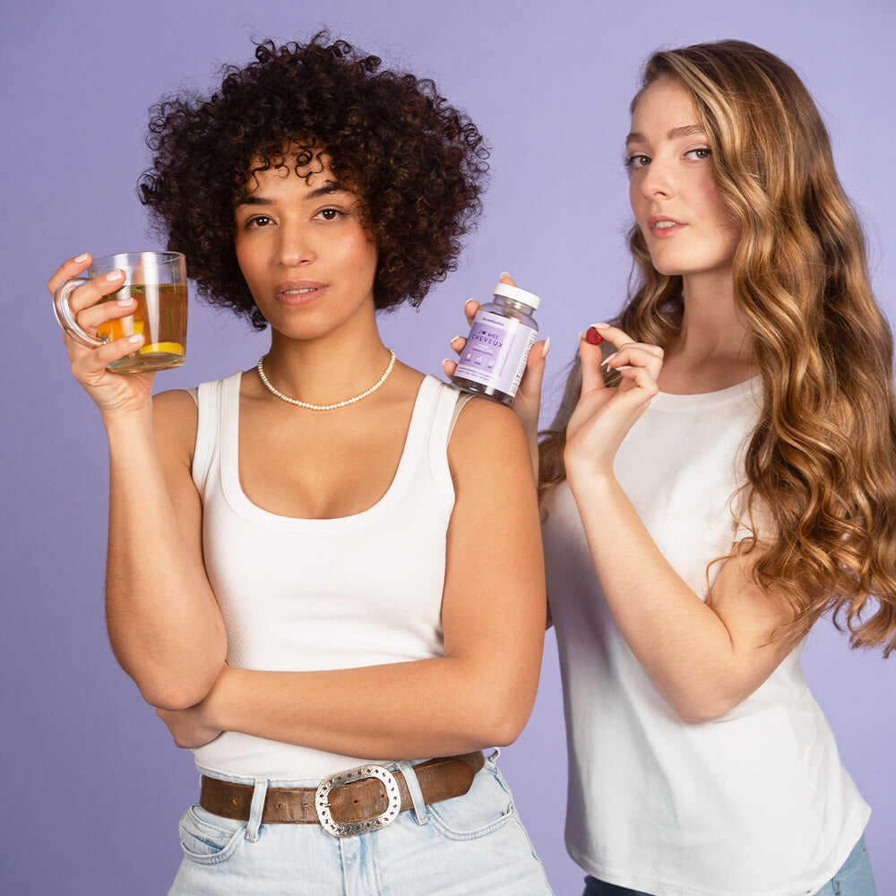 Deux femmes souriantes tenant une tasse de thé et le pack Coup de Pousse Les Confiantes, soins naturels pour stimuler la croissance des cheveux.